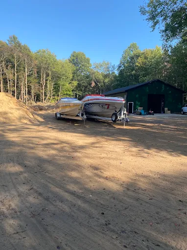 Two completed performance boats on trailers outside the shop