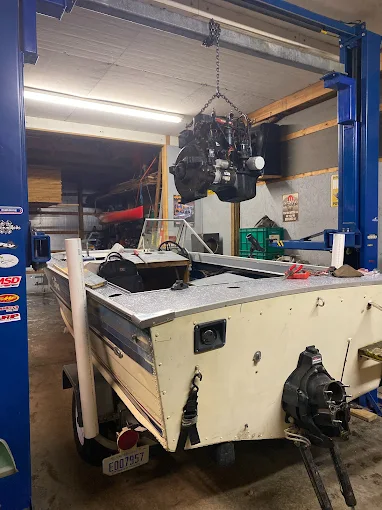 Engine being lifted out of an aluminum boat on a hoist
